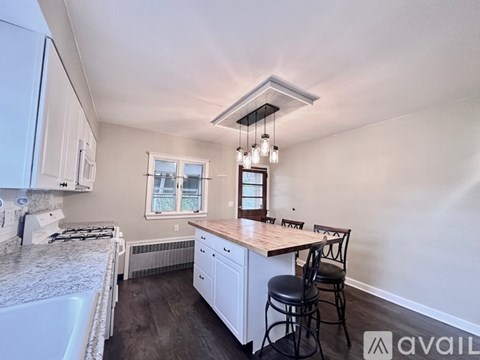 A kitchen with white cabinets and a wooden island.