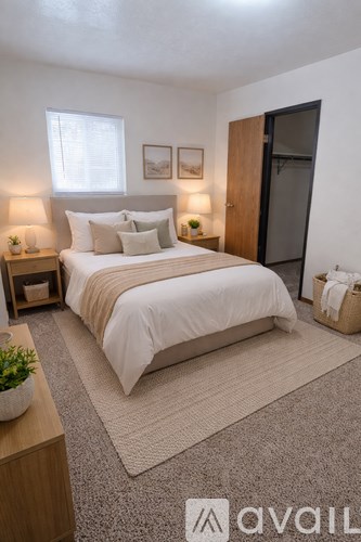 A bedroom with a large bed, two lamps, and a plant on a nightstand.