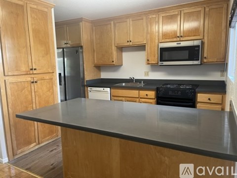 A kitchen with wooden cabinets and a black countertop.