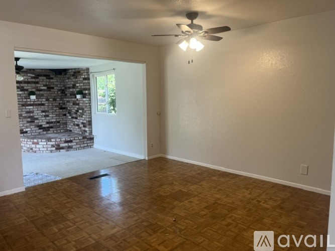 A room with a ceiling fan and wooden flooring.