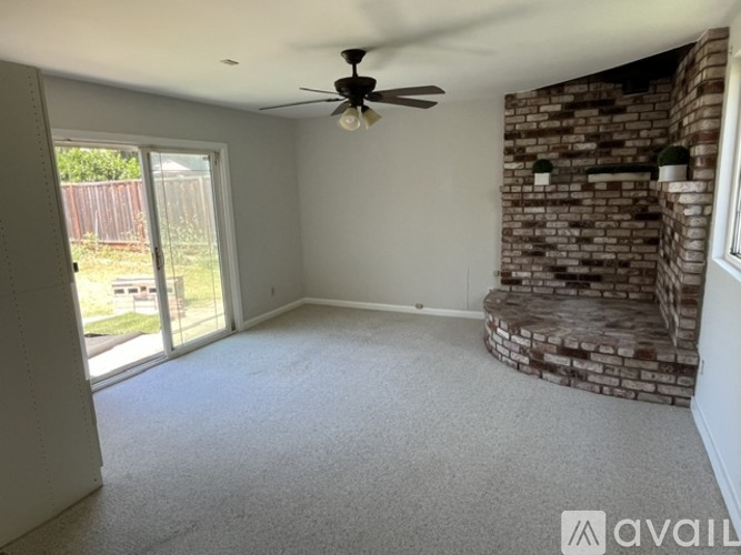 A room with a ceiling fan and a brick wall.