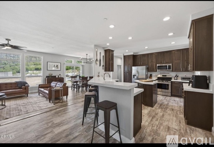 A spacious kitchen and living room with wooden floors and modern appliances.