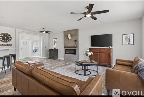 A living room with a brown couch and a ceiling fan.