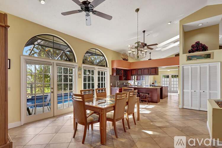 A dining room with a table set for six with a view of the pool outside.