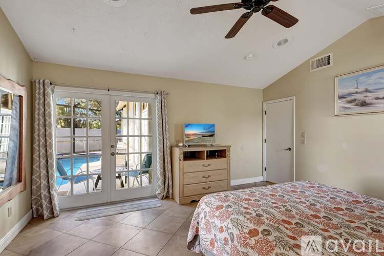 A bedroom with a bed, dresser, and sliding glass doors leading to a pool.