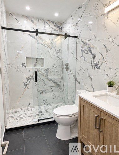 A bathroom with a marble wall and a walk-in shower.
