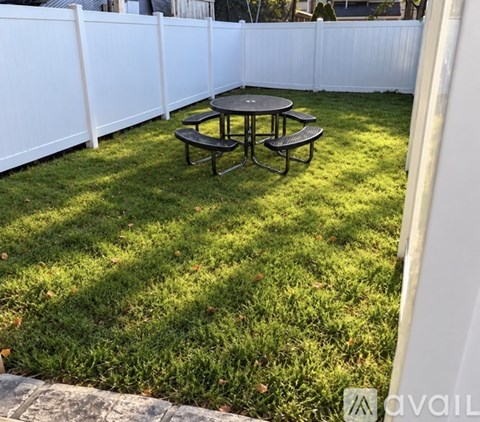 A backyard with a white fence and a round picnic table.