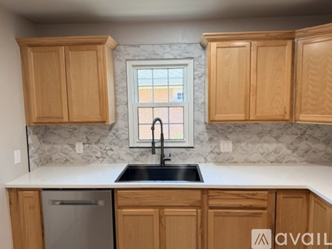 A kitchen with wooden cabinets and a marble backsplash.