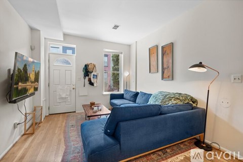 A living room with a blue couch and a painting on the wall.