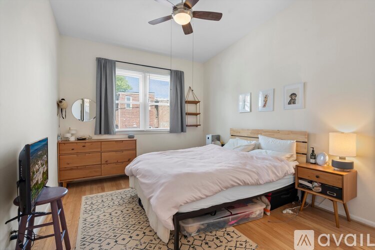 A bedroom with a bed, dresser, and a ceiling fan.