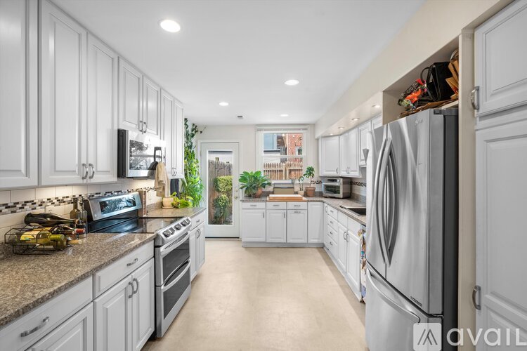 A modern kitchen with white cabinets and stainless steel appliances.