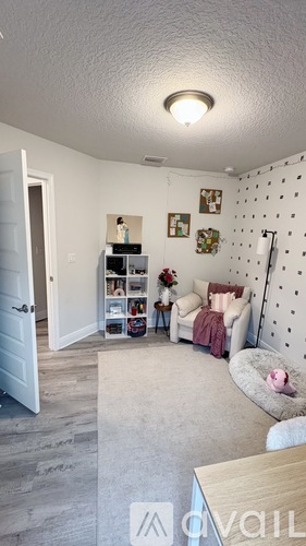 A living room with a white wall and a grey carpet.