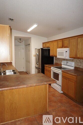 A kitchen with wooden cabinets and a black refrigerator.