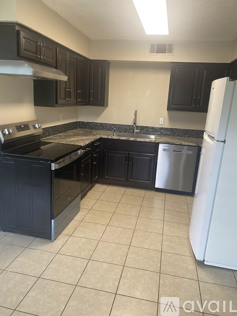 A kitchen with black cabinets and a white refrigerator.