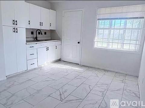 A kitchen with white cabinets and a marble floor.