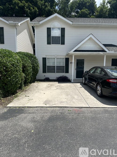 A white house with a black car parked in front.