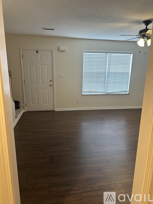 A room with a door, a window with blinds, and a ceiling fan.