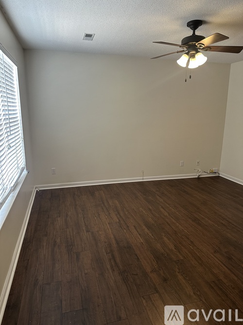 A room with a ceiling fan and wooden flooring.