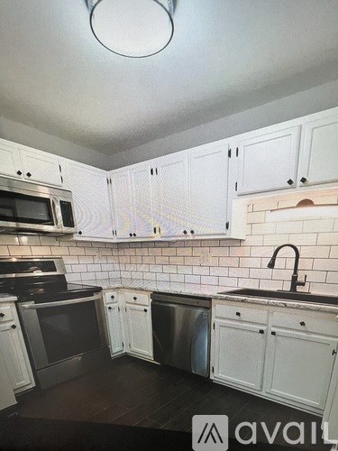 A kitchen with white cabinets and a black stove top oven.