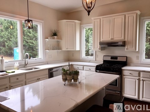 A kitchen with white cabinets and a marble countertop.