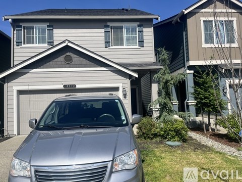 A silver car is parked in front of a house.