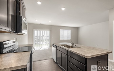 A kitchen with dark brown cabinets and a granite countertop.