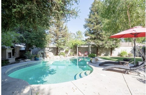 A red umbrella is next to a pool.
