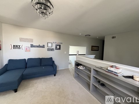 A living room with a blue couch and a chandelier.