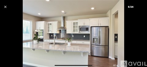 A modern kitchen with a stainless steel refrigerator and a marble countertop.