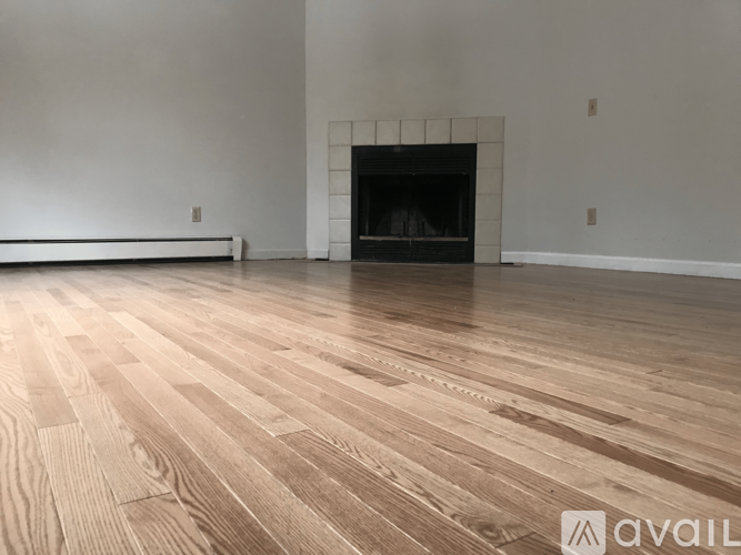 A room with a fireplace and wooden flooring.