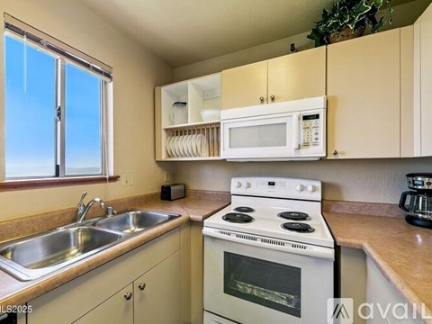 A kitchen with a white stove top oven and a white microwave above it.