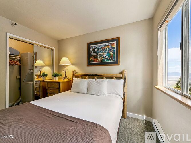 A bedroom with a large bed, a nightstand with a lamp, and a painting on the wall.