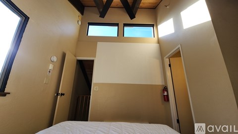 A bedroom with a large bed, a nightstand with a lamp, and a painting on the wall.
