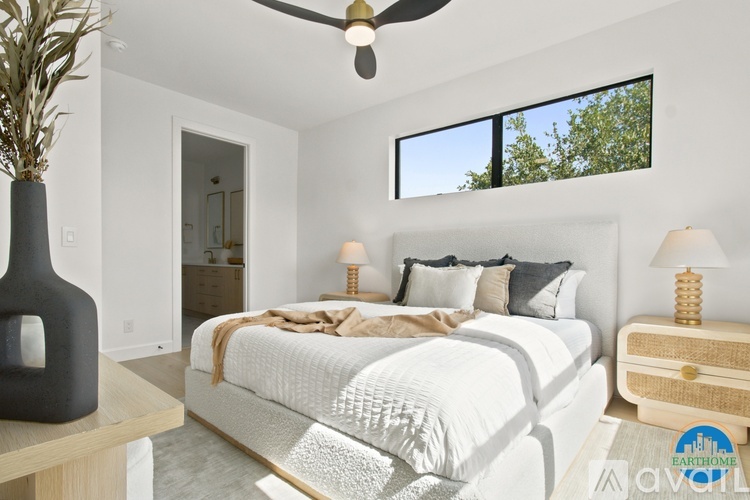 A bedroom with a large bed, a ceiling fan, and a vase on a table.