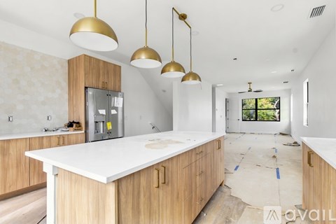 A kitchen under construction with wooden cabinets and white countertops.