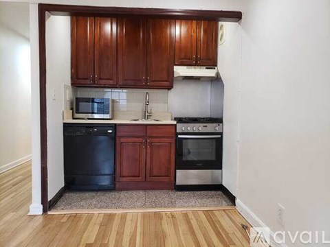 A kitchen with wooden cabinets and a black dishwasher.