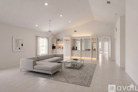 A spacious living room with a grey sofa and a glass coffee table.