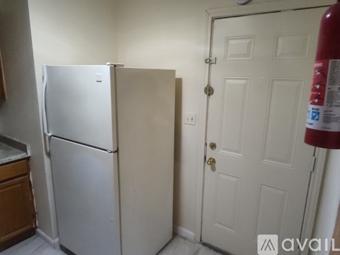 A white refrigerator is in a kitchen next to a white door.