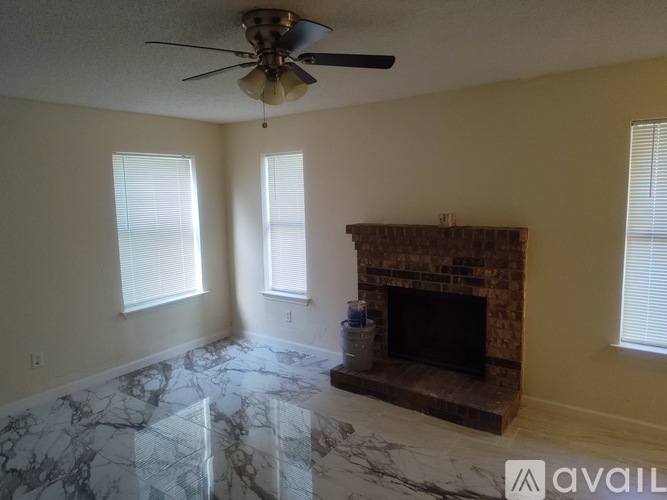 A living room with a fireplace and a fan.