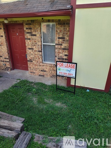 A red door and a sign that says "for lease" in front of a brick building.