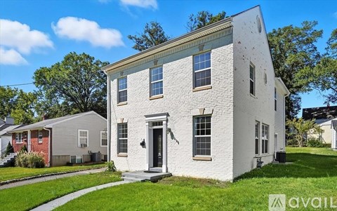 A white two-story house with a black door and windows.