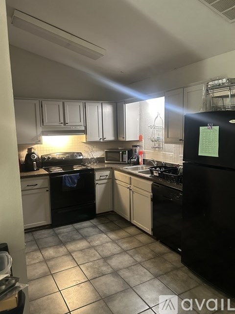 A kitchen with black appliances and white cabinets.
