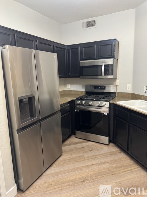 A kitchen with a stainless steel refrigerator and black cabinets.
