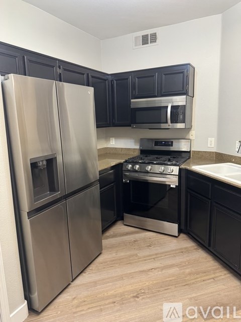 A kitchen with a stainless steel refrigerator and black cabinets.