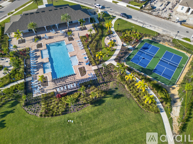 An aerial view of a resort with a tennis court, swimming pool, and palm trees.