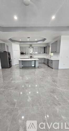 A spacious kitchen with a refrigerator, sink, and cabinets.