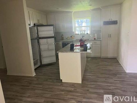 A kitchen with a refrigerator, island, and cabinets.