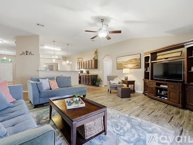 A living room with a grey couch, a coffee table, and a television.