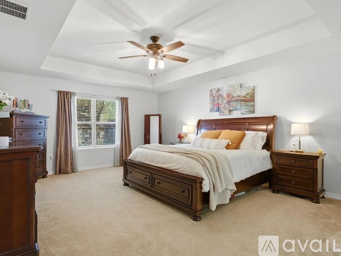 A bedroom with a large bed, a dresser, and a ceiling fan.