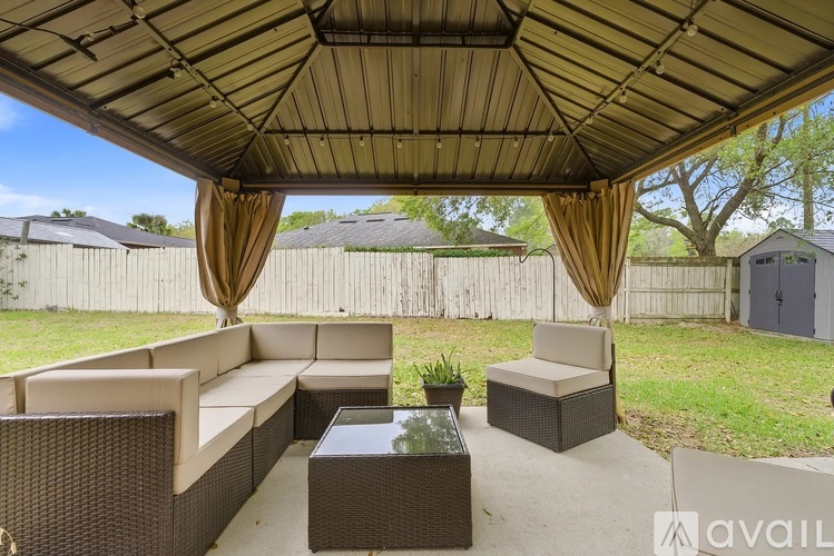A patio with a couch, chairs, and a table under a canopy.